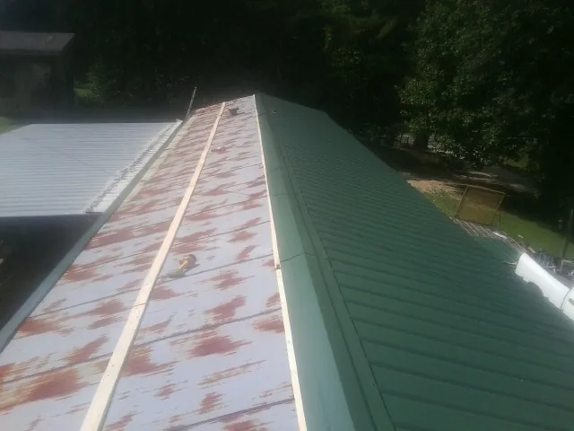 Old rusted panels beside newly installed green metal roofing — Wind Damage Roof Repair by Roofing Brothers in Fowler
