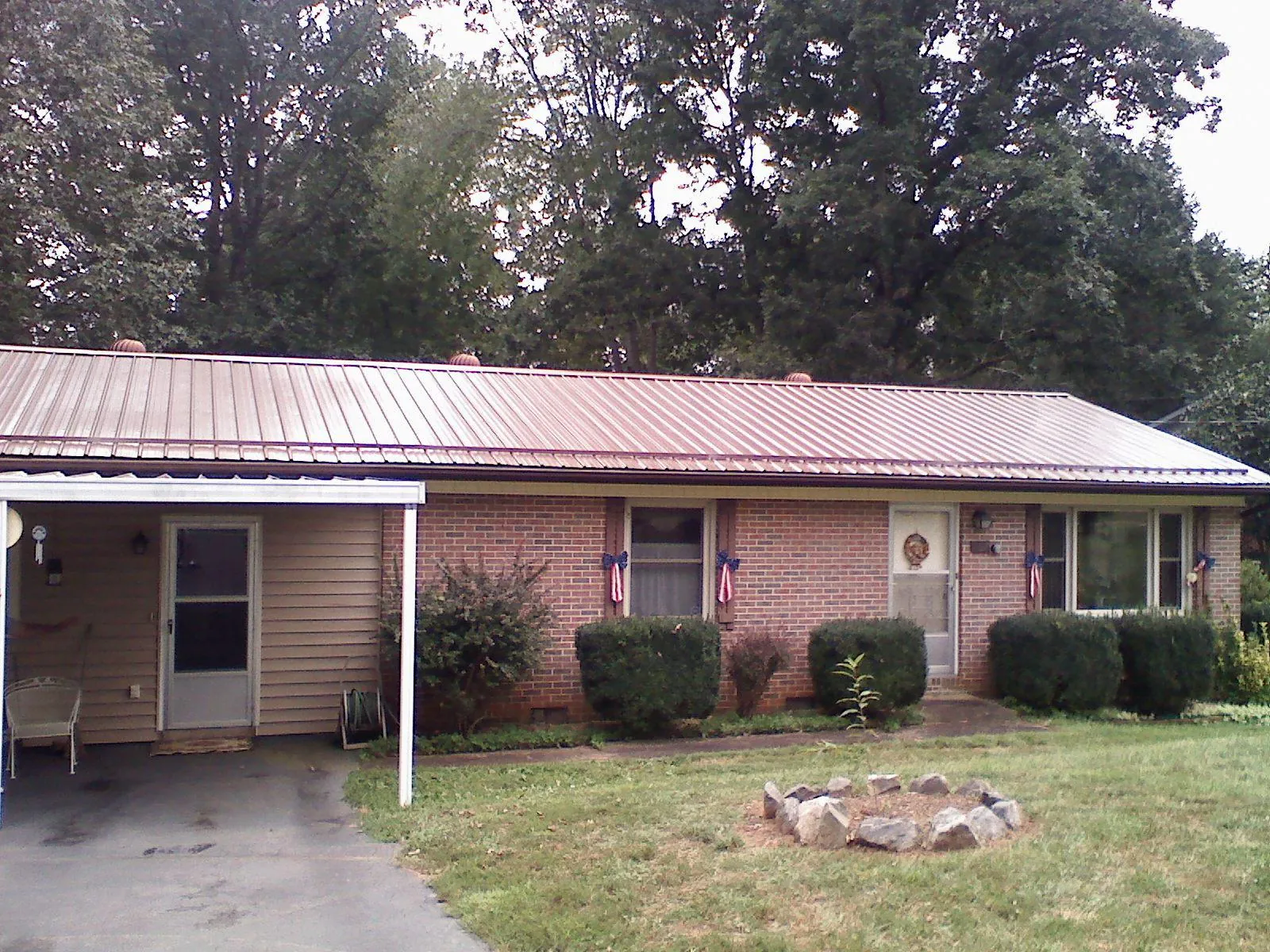 Bronze metal roof and carport on a brick ranch home — Roof Repair work by our crew in Fowler