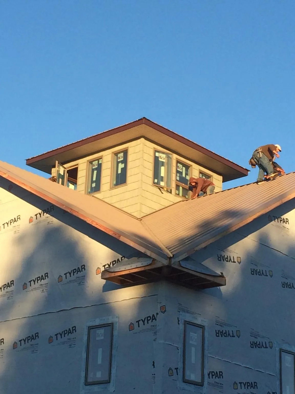 Roofers working around a rooftop cupola on a new metal roof at sunset — Roof Waterproofing in Fowler by Roofing Brothers